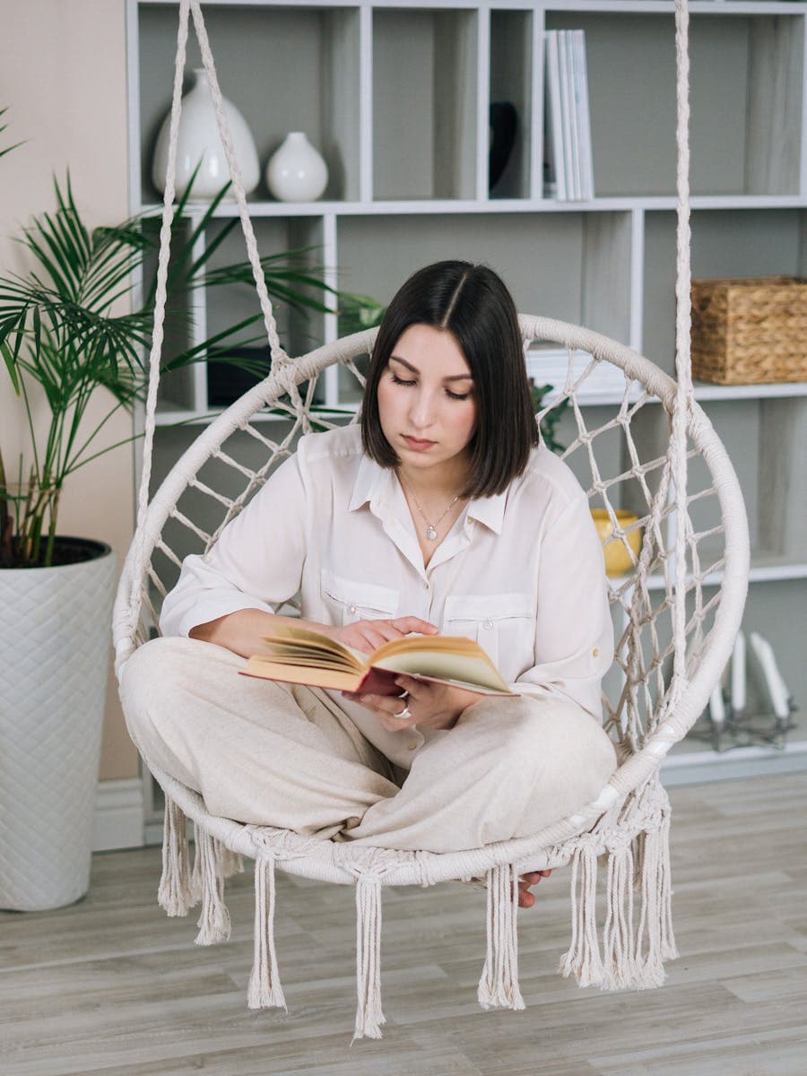 Woman relaxing in an indoor hanging chair surrounded by plants